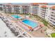 Aerial view of sparkling pools, beachfront, and rows of lounge chairs and orange umbrellas at 5501 S Atlantic Ave # 4090, New Smyrna Beach, FL 32169