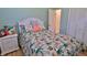 Comfortable bedroom with light blue walls, tropical bedding, a white headboard, and wood flooring at 585 Corbin Park Rd, New Smyrna Beach, FL 32168