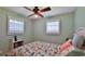 Cozy bedroom with a ceiling fan, natural light from shuttered windows, and a comfy bed with tropical-themed bedding at 585 Corbin Park Rd, New Smyrna Beach, FL 32168