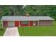Charming single-story home featuring red siding, brick accents, a well-maintained lawn, and a convenient attached garage at 585 Corbin Park Rd, New Smyrna Beach, FL 32168