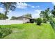 Spacious backyard featuring a well-maintained lawn, white fence, and a screened-in lanai at 5935 Shady Creek Ln, Port Orange, FL 32128