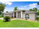 Inviting single-story home with arched windows, lush front lawn, and manicured landscaping at 5935 Shady Creek Ln, Port Orange, FL 32128