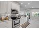 Bright kitchen with white cabinets, stainless steel appliances, and marble countertops opening to the dining area at 620 Middlebury Loop, New Smyrna Beach, FL 32168