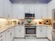 Bright kitchen features white cabinetry, stainless steel appliances, and a decorative tile backsplash at 6307 Hanfield Dr, Port Orange, FL 32128
