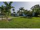 Exterior view of light blue home, showcasing a well-manicured lawn, driveway, and palm trees at 653 Goodwin Ave, New Smyrna Beach, FL 32169