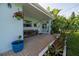 Charming front porch with brick flooring, a hanging basket, wooden bench, and a vibrant plumeria tree at 653 Goodwin Ave, New Smyrna Beach, FL 32169