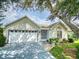 Inviting home exterior with a well-manicured lawn, mature tree, and two-car garage at 686 Middlebury Loop, New Smyrna Beach, FL 32168