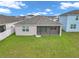 Back exterior view featuring a screened in porch and a grassy yard at 7223 Sw 61St Pl, Ocala, FL 34474