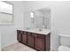 Bright bathroom showcasing a double vanity with a dark wood cabinet and a toilet at 7223 Sw 61St Pl, Ocala, FL 34474