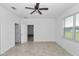 A bedroom has light neutral walls, a ceiling fan, and a window that allows light to enter the room at 7223 Sw 61St Pl, Ocala, FL 34474