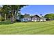 Landscaped front yard of a beautiful home with a manicured lawn, flowering plants and mature trees at 798 Fairway Dr, New Smyrna Beach, FL 32168