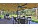 Covered patio with outdoor dining area, grill, ceiling fans and views of the manicured backyard at 798 Fairway Dr, New Smyrna Beach, FL 32168