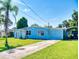 A light blue home features a front lawn and driveway that lead to a carport at 903 Conrad Dr, New Smyrna Beach, FL 32168