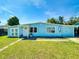 Charming light blue single-story home featuring a well-kept lawn, plants, and a welcoming entrance at 903 Conrad Dr, New Smyrna Beach, FL 32168