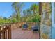 Outdoor deck featuring wood railing, chairs, plants, and a stone accent wall, perfect for relaxation and enjoying the surroundings at 934 N Halifax Ave, Daytona Beach, FL 32118