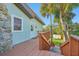 Charming home exterior with a white door, wood staircase and stone accent wall surrounded by mature tropical trees at 934 N Halifax Ave, Daytona Beach, FL 32118