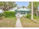 Charming home featuring a screened front porch and lush green landscaping at 102 N Brooks Cir, Oak Hill, FL 32759