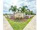 Welcome to Woodbridge Lakes! A beautifully landscaped entrance with palm trees and decorative fencing at 103 Old Mill Pond Rd, Edgewater, FL 32141