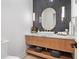 Contemporary powder room with wood vanity, marble countertop, oval mirror and modern vertical tiled accent wall at 1616 Turnbull Crossings Dr, New Smyrna Beach, FL 32168