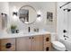 Modern bathroom with wooden vanity, round mirror, matte black fixtures, and white subway tile tub surround at 1616 Turnbull Crossings Dr, New Smyrna Beach, FL 32168