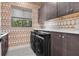 Laundry room with modern washer and dryer, cabinets and designer wallpaper at 1616 Turnbull Crossings Dr, New Smyrna Beach, FL 32168