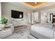 Bright, modern main bedroom with a tray ceiling, TV, and access to the ensuite bathroom at 1616 Turnbull Crossings Dr, New Smyrna Beach, FL 32168