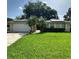 Charming single-story home featuring a manicured lawn, complemented by tropical palm trees and solar panels at 1743 Jacobs Rd, South Daytona, FL 32119