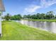 A serene backyard view of a waterfront home, enhanced by lush green grass, trees and blue sky at 1809 Forough Cir, Port Orange, FL 32128