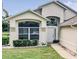 Welcoming home entrance featuring a large arched window, well-manicured shrubs, and a paved walkway at 1809 Forough Cir, Port Orange, FL 32128