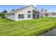 Rear of a home featuring a screened lanai with table, chairs, and a large grassy lawn near a community pond at 1809 Forough Cir, Port Orange, FL 32128