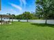 Large grassy backyard with a white fence, mature trees and a pergola covered dining area at 19 Abacus Ave, Ormond Beach, FL 32174