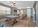 Living room featuring plank floors, a stone fireplace, billiards, and a ceiling fan at 19 Abacus Ave, Ormond Beach, FL 32174