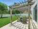 Covered outdoor dining area under a pergola, surrounded by a green lawn and a privacy fence at 19 Abacus Ave, Ormond Beach, FL 32174