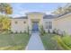 Inviting single-story home with a blue front door, manicured lawn, and lush landscaping at 1929 Pioneer Trl, New Smyrna Beach, FL 32168