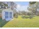 Backyard storage shed with blue doors surrounded by lush green lawn and mature trees at 1929 Pioneer Trl, New Smyrna Beach, FL 32168