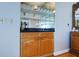 Wet bar including a sink, storage cabinets, mirrored backsplash, and granite countertop at 2300 N Atlantic Ave # 203, Daytona Beach, FL 32118