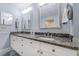 Bathroom with granite-topped double vanity, framed mirrors, and neutral walls at 2300 N Atlantic Ave # 203, Daytona Beach, FL 32118