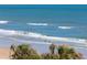 Picturesque beach scene with people enjoying the waves and soft sand, framed by palm trees in a coastal setting at 2300 N Atlantic Ave # 203, Daytona Beach, FL 32118
