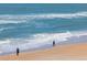 Coastal scene capturing the beauty of the beach with gentle waves and people enjoying a leisurely stroll at 2300 N Atlantic Ave # 203, Daytona Beach, FL 32118