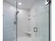 Walk-in shower featuring glass doors, a bench, and neutral tile at 2300 N Atlantic Ave # 203, Daytona Beach, FL 32118