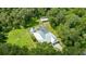 Aerial view of a lush property featuring a screened pool, metal roof home, and separate shed with a fenced backyard at 2360 Mooneyham Dr, New Smyrna Beach, FL 32168