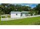 Rear view of home surrounded by a white picket fence and luscious green lawn at 2360 Mooneyham Dr, New Smyrna Beach, FL 32168