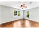 Well-lit bedroom with gleaming hardwood floors, a ceiling fan, and bright windows overlooking lush greenery at 2360 Mooneyham Dr, New Smyrna Beach, FL 32168