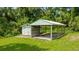 View of the detached garage and covered carport featuring lush greenery at 2360 Mooneyham Dr, New Smyrna Beach, FL 32168