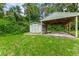 View of the detached garage and covered carport with a lush green lawn at 2360 Mooneyham Dr, New Smyrna Beach, FL 32168