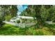 View of the home featuring a white picket fence surrounded by mature trees and green foliage at 2360 Mooneyham Dr, New Smyrna Beach, FL 32168