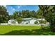 Side view of home surrounded by a white picket fence, lush lawn, and mature trees at 2360 Mooneyham Dr, New Smyrna Beach, FL 32168