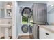 Bright laundry room with stacked washer/dryer, sink and a view to the lush yard at 2360 Mooneyham Dr, New Smyrna Beach, FL 32168
