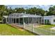 A screened in pool area in the backyard with a view of lush green grass and a white picket fence at 2360 Mooneyham Dr, New Smyrna Beach, FL 32168