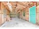 Unfinished interior of the shed showcasing bare wood framing, concrete floor, and a vibrant blue door at 2360 Mooneyham Dr, New Smyrna Beach, FL 32168